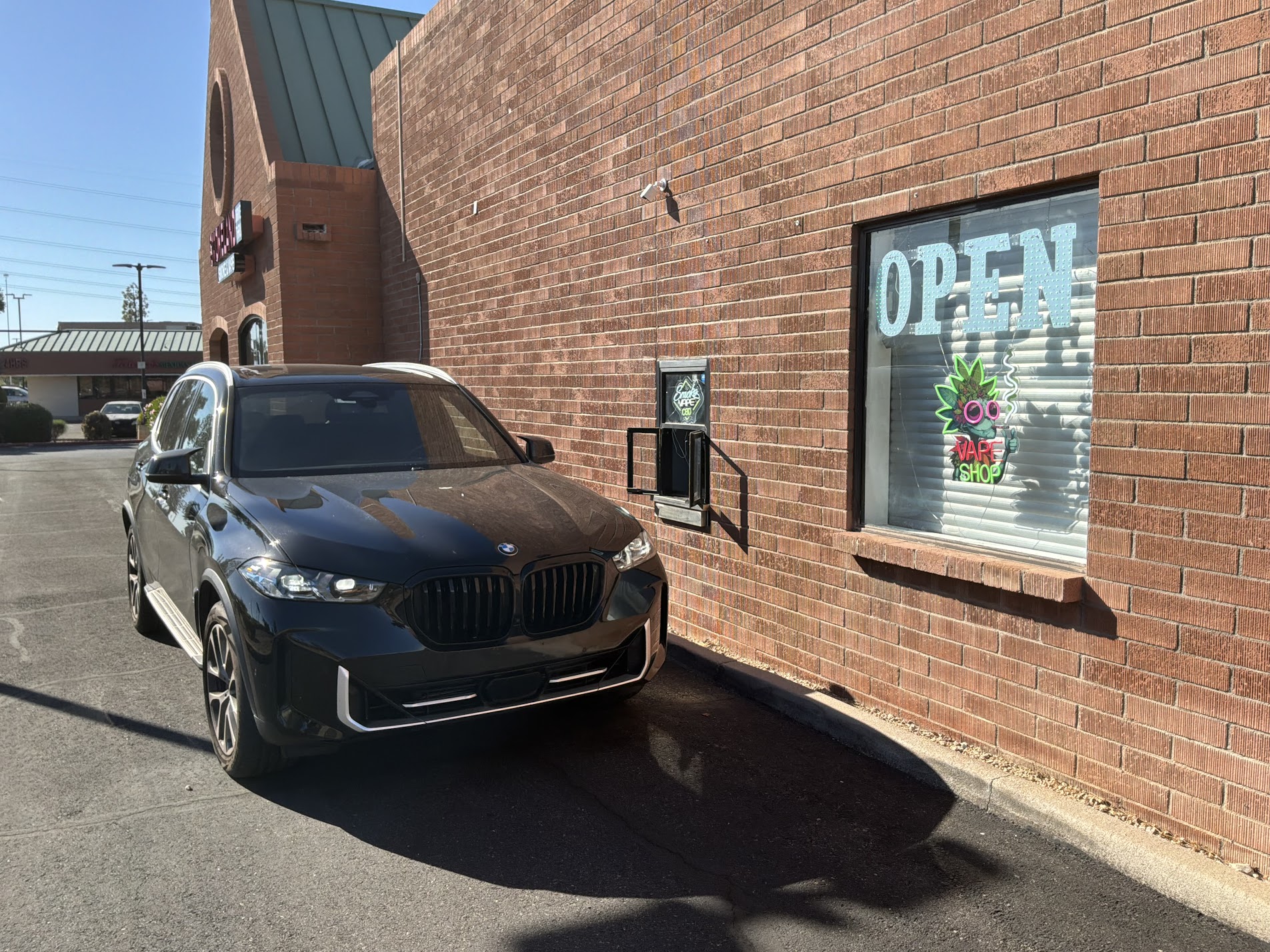 Smokeland drive-thru window in Glendale, AZ with neon Smoke & Vape signage